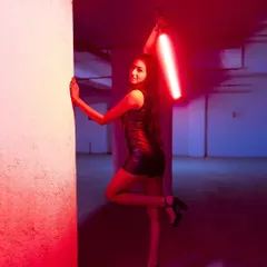 A futuristic and powerful pose, with the model holding a red light saber, creating a sci-fi inspired look in a gritty, urban setting.