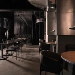 A long shot of the dining area at Lair, showcasing the fusion of raw elegance and bold minimalism. The interplay of stainless steel panels, dark leather seating, and carefully directed lighting creates a sophisticated yet industrial ambiance for this modern cocktail bar.