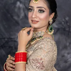 A beautiful reception or engagement look. The combination of a golden-beige lehenga with emerald green jewelry is perfectly complemented by soft glam makeup, focusing on luminous skin and defined eyes.