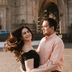 A candid moment of affection in front of a historic Mumbai landmark. The gentle breeze catching her hair adds a touch of spontaneous beauty to this engagement portrait.