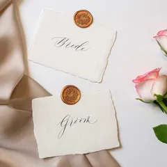 The elegance of modern calligraphy is perfect for weddings. These "Bride" and "Groom" place cards with wax seals are a beautiful example of how this script adds a touch of class.