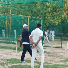 A young bowler gets direct instruction on his technique from Virender Sehwag. This hands-on approach ensures that fundamental skills are corrected and perfected early on.
