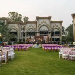A wide view of an outdoor event setup with a palace-like backdrop, featuring elegant table settings and a color palette of lavender and white.