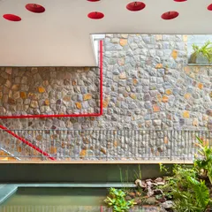 This view captures the essence of biophilic design. An indoor pond, filled with indigenous plants, sits below a ceiling dotted with inverted earthen pots, designed to encourage birds to nest and feel at home within the architecture.