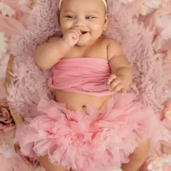 The pure, uninhibited joy of a four-month-old. Her giggles and chubby cheeks are just precious in this pink floral setup.
