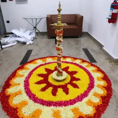 A large floral rangoli (pookalam) with a traditional lamp (diya) at the center, created for a corporate event at Trans cosmos.