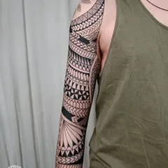 The side view of a completed Maori sleeve, displaying the seamless wrap-around design. The balance between dense blackwork and detailed patterns is key to creating a visually striking and authentic piece.