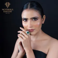 A regal statement piece. This ring features a large, pear-shaped emerald surrounded by a floral halo of brilliant diamonds, designed to capture attention and admiration.
