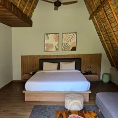 Inside our A-Frame cottage, you'll find a spacious, airy retreat. The high, thatched roof and modern wooden furnishings create a warm and inviting atmosphere for you to relax in.