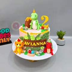 A cute dinosaur-themed cake for Avianna's 2nd birthday, featuring friendly fondant dinosaurs, a volcano, and jungle leaves.