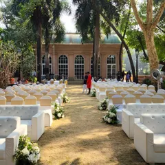 A wider view of the outdoor ceremony, showing the comfortable white lounge sofas for VIP guests in the front rows. The majestic palm trees of the venue add to the grand and tropical feel of the setting.