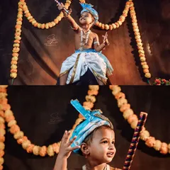 A full-body shot showing the complete little Krishna costume and pose. The marigold garland backdrop and traditional props create an authentic festive atmosphere for this creative kids' portrait.