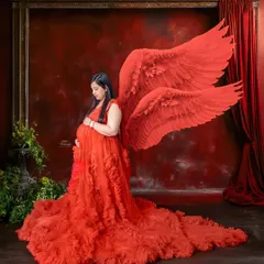 A full-length view of our red angel wings and ruffled gown. This studio setup is perfect for creating a bold, artistic, and unforgettable maternity portrait.