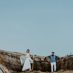 A wide-angle shot of a couple posing on a rustic, abandoned boat in Alibag. This unique prop adds a powerful, story-driven element to their beach pre-wedding shoot.