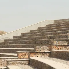 The tiered seating of the amphitheatre follows the natural contours of the hill. The combination of rough stone-filled gabions and smooth concrete tops creates a textural contrast that is both rustic and refined.