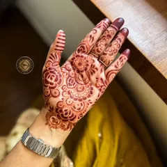 A lovely, dark henna stain on display, perfect for Eid celebrations. The design is a classic floral pattern that fills the palm beautifully.