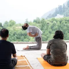 We integrate gentle physical practices like yoga to prepare the body for deep meditation. Here, a participant performs the Camel Pose (Ustrasana) during a mountain retreat, opening the heart and connecting with the expansive natural landscape around us.