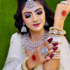 A bride in a white outfit adorned with a full American Diamond set, including a choker, maang tikka, and matching white bangles. The look is modern yet traditional.