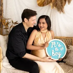 And it's a boy! The couple's happy expressions say it all as they hold up a sign announcing the wonderful news in a cozy boho setting.