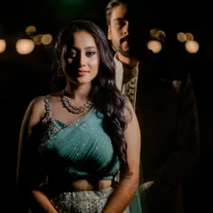 A dramatic portrait using shadow and light. The bride is illuminated while the groom remains partially in shadow, creating a moody and mysterious image with a cinematic feel.