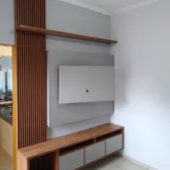 This TV unit features a combination of wood-fluted paneling and a simple grey back panel. The design includes an open shelf and a low console with drawers, offering both display space and concealed storage.