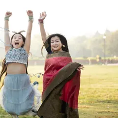 A mother and daughter share a moment of pure joy, jumping in the air during their outdoor family photoshoot. The open space allows for so much fun and natural expression.