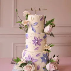 For the big days, we love creating something truly special. This three-tiered wedding cake features delicate, hand-painted watercolor flowers in shades of lavender and is adorned with fresh roses, making it a beautiful centerpiece for a memorable celebration.