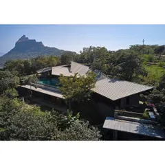 An aerial view of the Lateral Verandah House shows how the structure is nestled into the lush green hillside, its form dictated by the natural contours of the land.