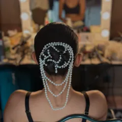 A behind-the-scenes close-up of the pearl style bun. This view highlights the detailed craftsmanship involved in weaving the pearl accessories into the hair for a flawless finish.