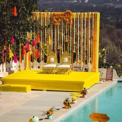 A perfect poolside Haldi setup. The stage is decorated with traditional marigold strings and colorful tassels, overlooking the water for a fun, festive vibe.
