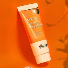 A flat lay of The Derma Co's sunscreen with a smear of the product shows its texture. The use of shadow play on a bold orange background creates a modern, graphic look for the brand.