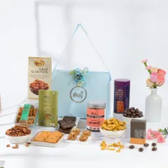 A beautifully arranged Rakhi gift hamper in a light blue bag. This assortment includes salted almonds, mini chiplets, chocolate covered nuts, and other snacks, offering a mix of sweet and savory flavors.