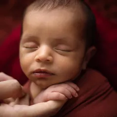 A parent's gentle hand holding their baby's chin. This shot is about connection and scale, showing just how small and protected they are in your hands.