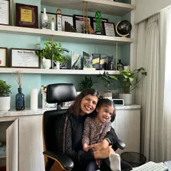 In my personal life, I'm a mom to two young girls and two furry babies. This is me with my daughter in my office, a space that represents the blend of my professional and personal worlds.