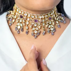 A close-up of a beautiful kundan choker with delicate purple stone drops. This piece combines traditional craftsmanship with a touch of modern color, making it versatile for various occasions.