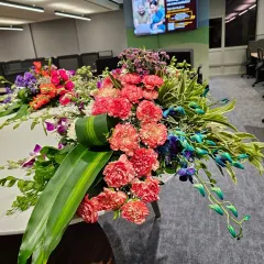 A large, lush floral arrangement designed for a main table or reception area. This bouquet features a mix of carnations, orchids, and other seasonal flowers for a vibrant look.