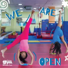 We are open. This vibrant image of two gymnasts mid-cartwheel perfectly captures the energy and excitement you will find at The Little Gym. Our space is ready for your child's next adventure.