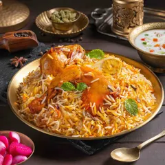 A magnificent Chicken Biryani, styled with whole spices and fresh mint. The focus is on the long-grain basmati rice and succulent chicken pieces, creating an image that speaks of authentic flavor and aroma for The Mughal House.