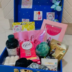A peek inside our custom bridal hamper, packed in a reusable blue trunk. This one is filled with pamper essentials from The Body Shop, a "Boss Babe" frame, a "Team Bride" sash, and sweet treats to celebrate the bride-to-be.