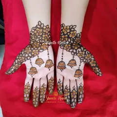 A playful and fancy design with delicate floral vines and hanging jhumka (earring) motifs that seem to dangle from the fingers.