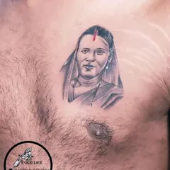 A chest portrait tattoo honoring a mother. The red bindi adds a touch of color and cultural significance to this beautiful black and grey piece.