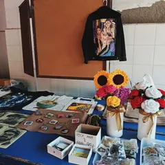 A wider view of my table setup at an event. You can see a variety of my work on display, from finished jackets and art prints to smaller custom items.