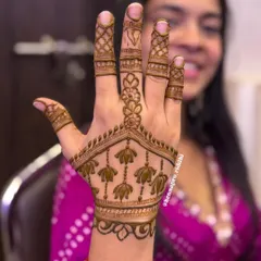 Minimalist henna can still have playful details. This design features a simple floral vine and a hanging lotus pattern, with a tiny, cute samosa shape hidden at the top for fun.