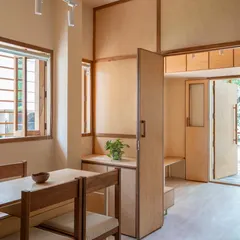 The waiting and consultation area is filled with natural light, with simple wooden furniture and a connection to the green space outside.