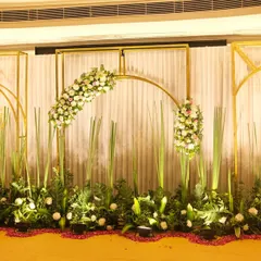 This photo shows a close-up of the golden arch framework and white floral arrangements against a textured white curtain. The design is perfect for creating a luxurious and modern photo wall or stage backdrop.