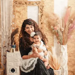 A warm and happy moment between mother and daughter. The earthy, boho-chic studio setup with dried palms and soft textures provides a beautiful, natural setting for their portrait.