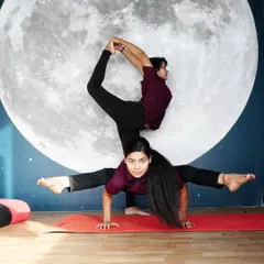 This stunning two-person pose in front of our moon mural is a beautiful example of the artistry and strength of Acro Yoga. It requires immense trust and coordination.