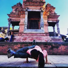 Astavakrasana, the Eight-Angle Pose, practiced in front of a temple in Nepal. Arm balances require a combination of strength, flexibility, and concentration.