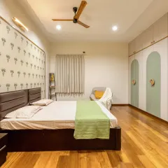A wider view of the parents' bedroom, showing the solid wood flooring and the custom hand-painted floral knobs on the wardrobes, adding a touch of quiet elegance.