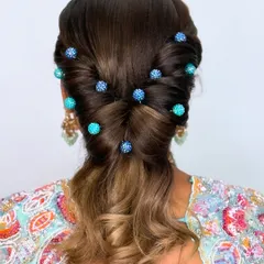 A chic and modern twisted ponytail hairstyle, decorated with trendy blue beaded pins for a unique and colorful touch.